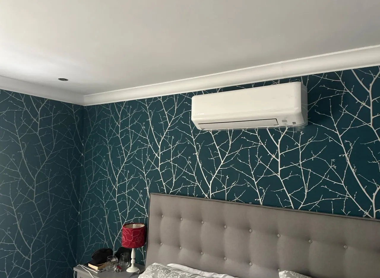 Wall-mounted air conditioning unit installed on a patterned bedroom feature wall