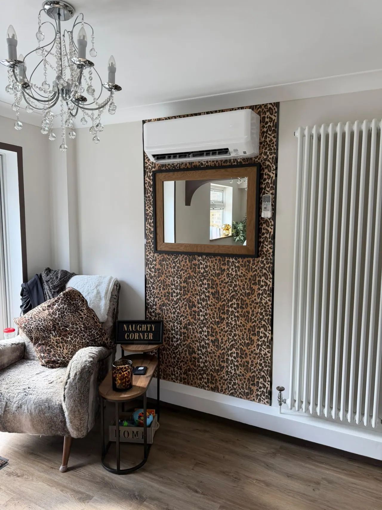 Wall-mounted air conditioning unit installed above a mirror in a living room
