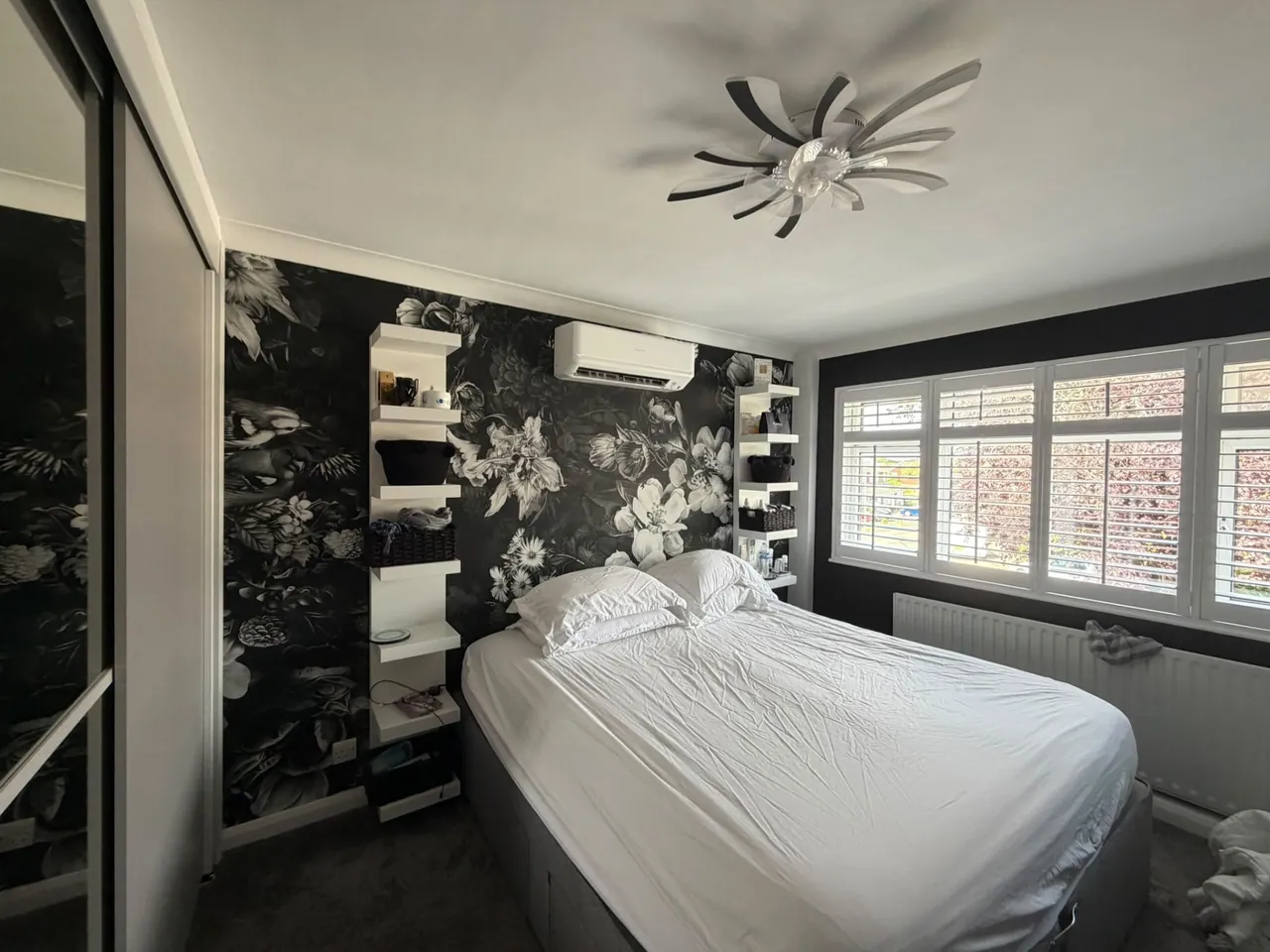 Wall-mounted air conditioning unit installed in a bedroom with floral wallpaper