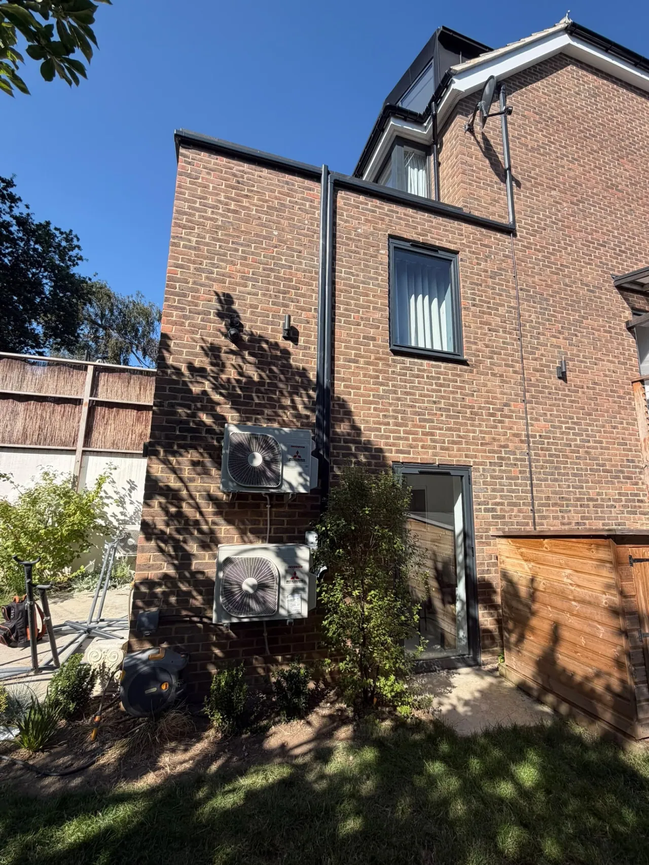 Two Mitsubishi air conditioning outdoor condensers on a brick home