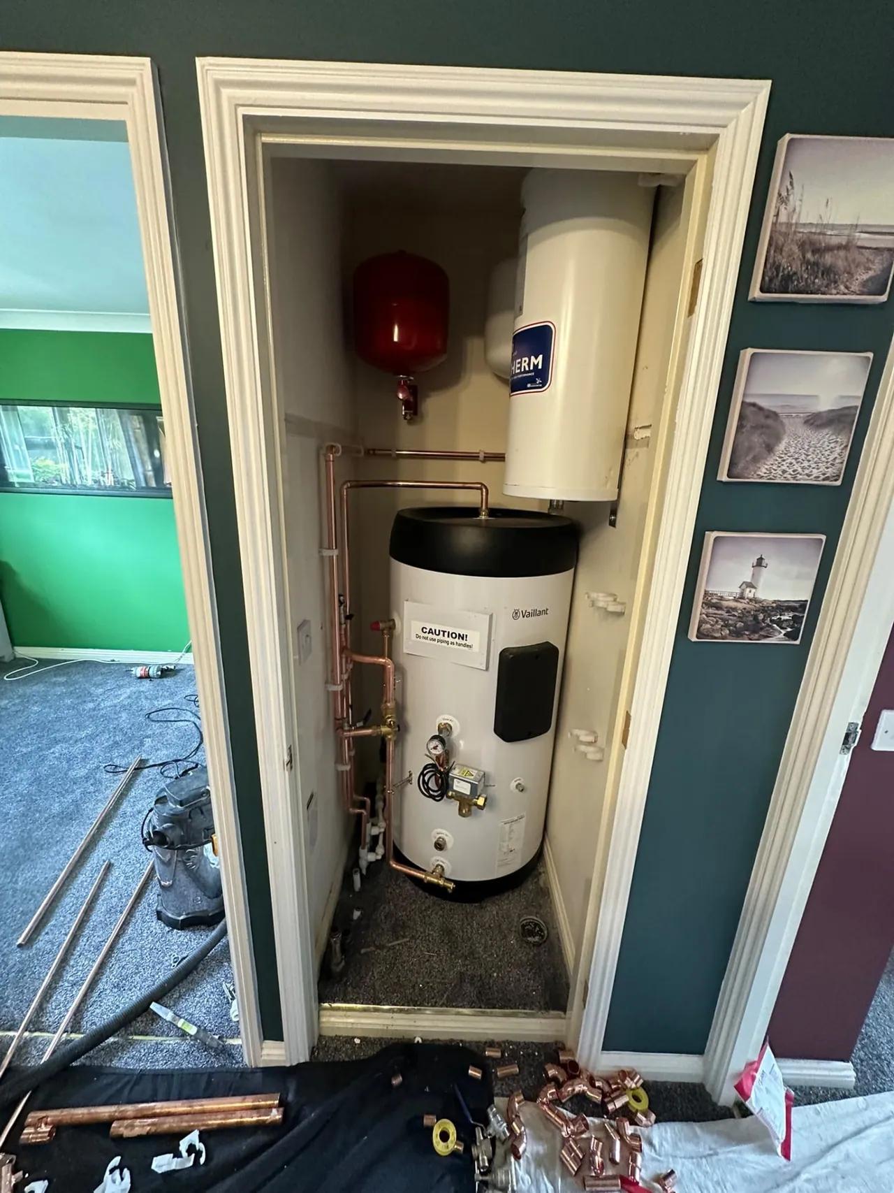 Heat pump hot water cylinder being installed in a hallway cupboard