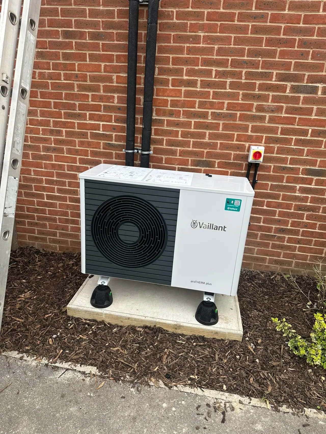 Vaillant air source heat pump outdoor unit beside a brick wall