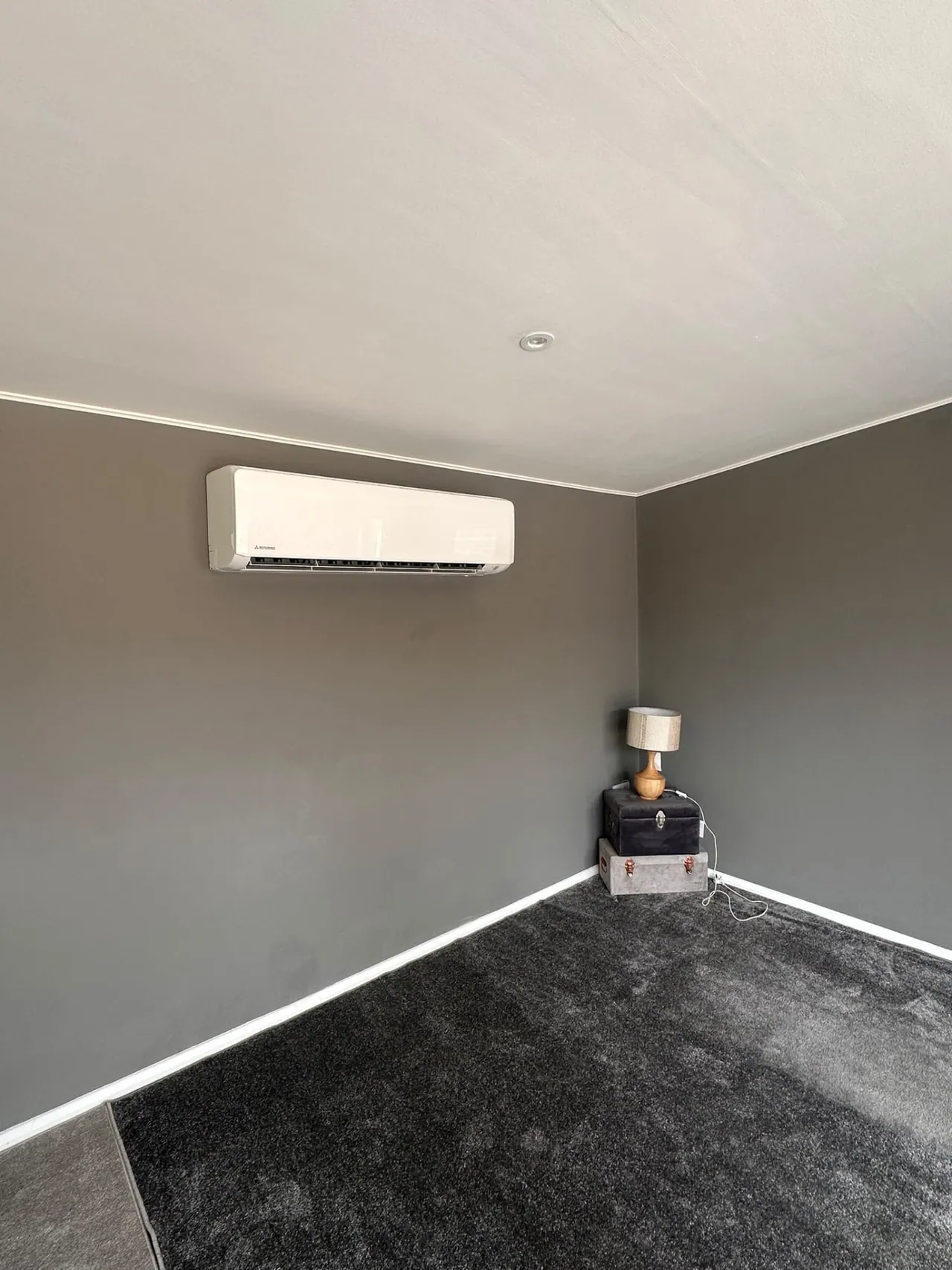 Wall-mounted air conditioning unit installed in a grey bedroom