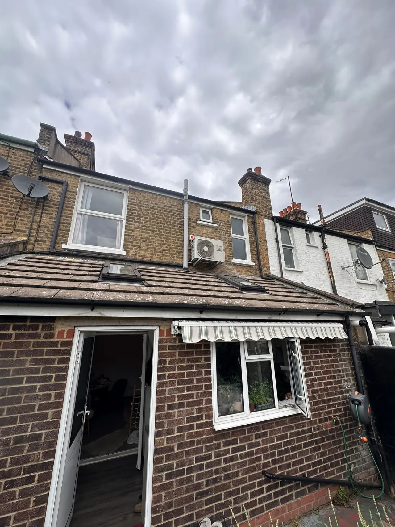Mitsubishi air conditioning outdoor condenser installed on the rear wall of a brick terrace