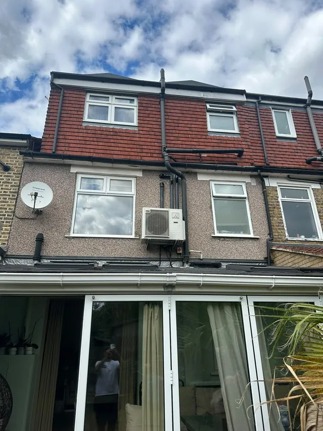 Mitsubishi air conditioning outdoor condenser installed on the rear wall of a terraced home