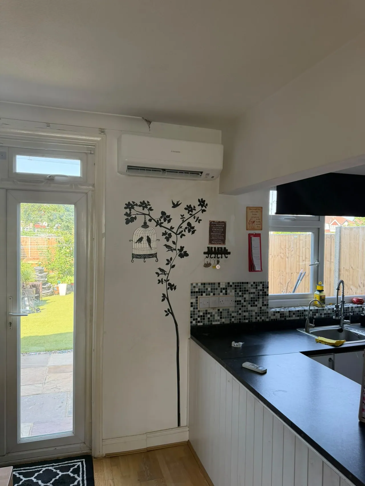 Wall-mounted air conditioning unit installed above a kitchen with garden doors