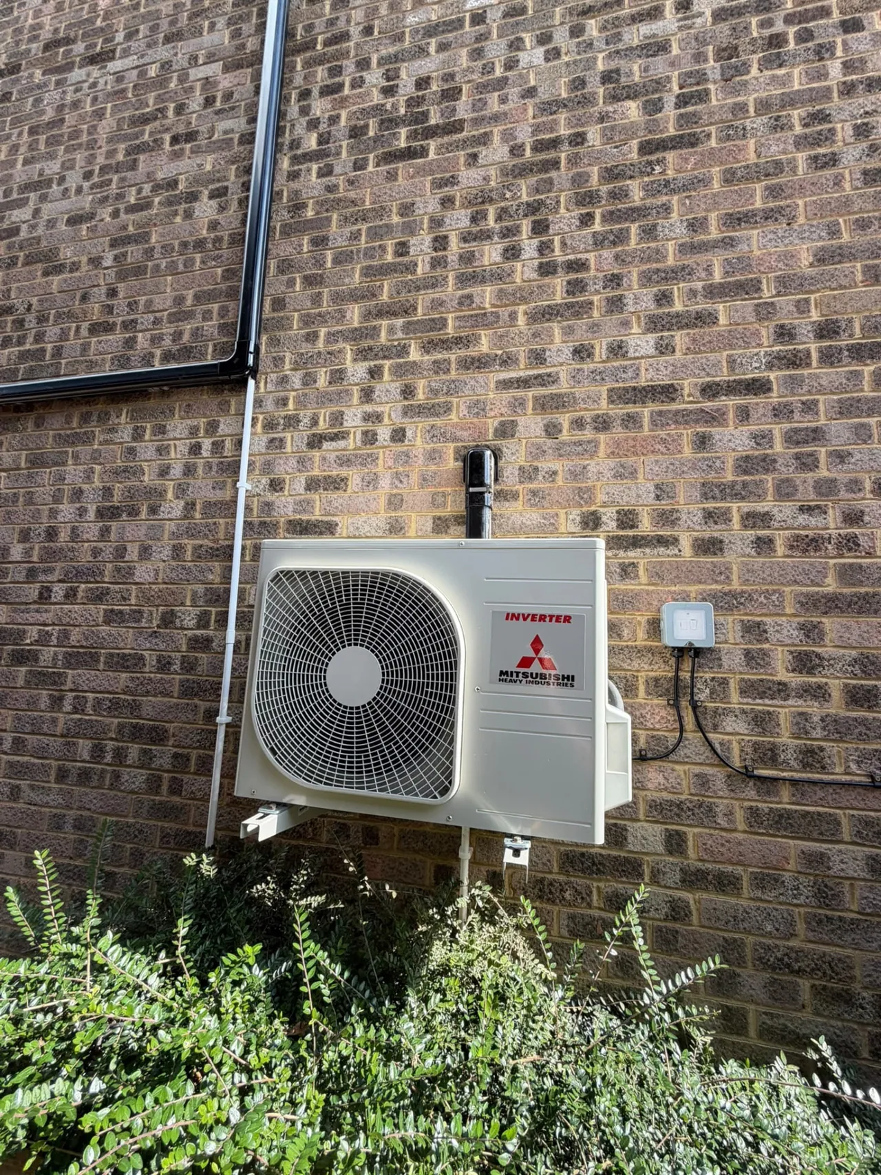 Mitsubishi air conditioning outdoor condenser installed on a brick wall