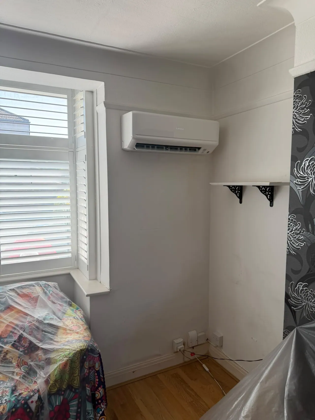 Wall-mounted air conditioning unit installed in a bedroom beside a window, South East London