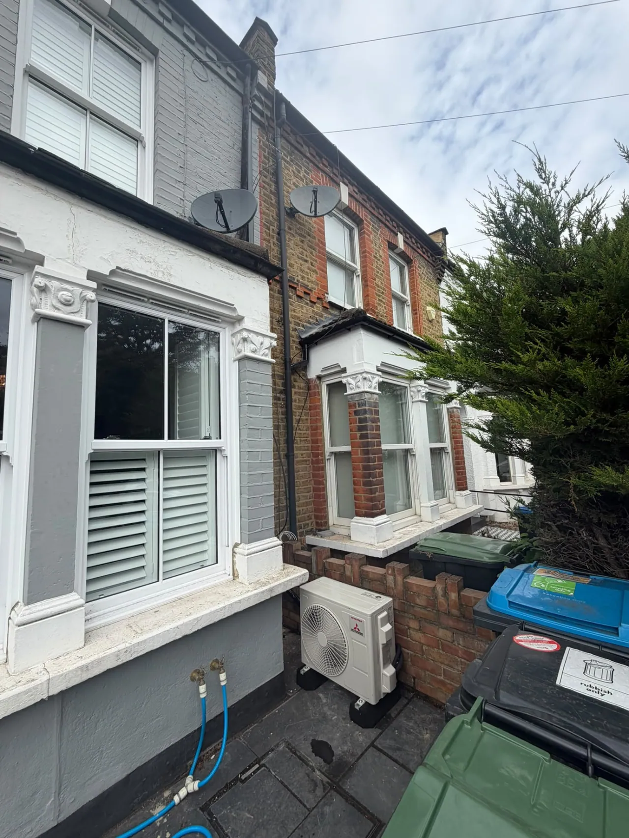 Mitsubishi air conditioning outdoor condenser installed beside a terraced house
