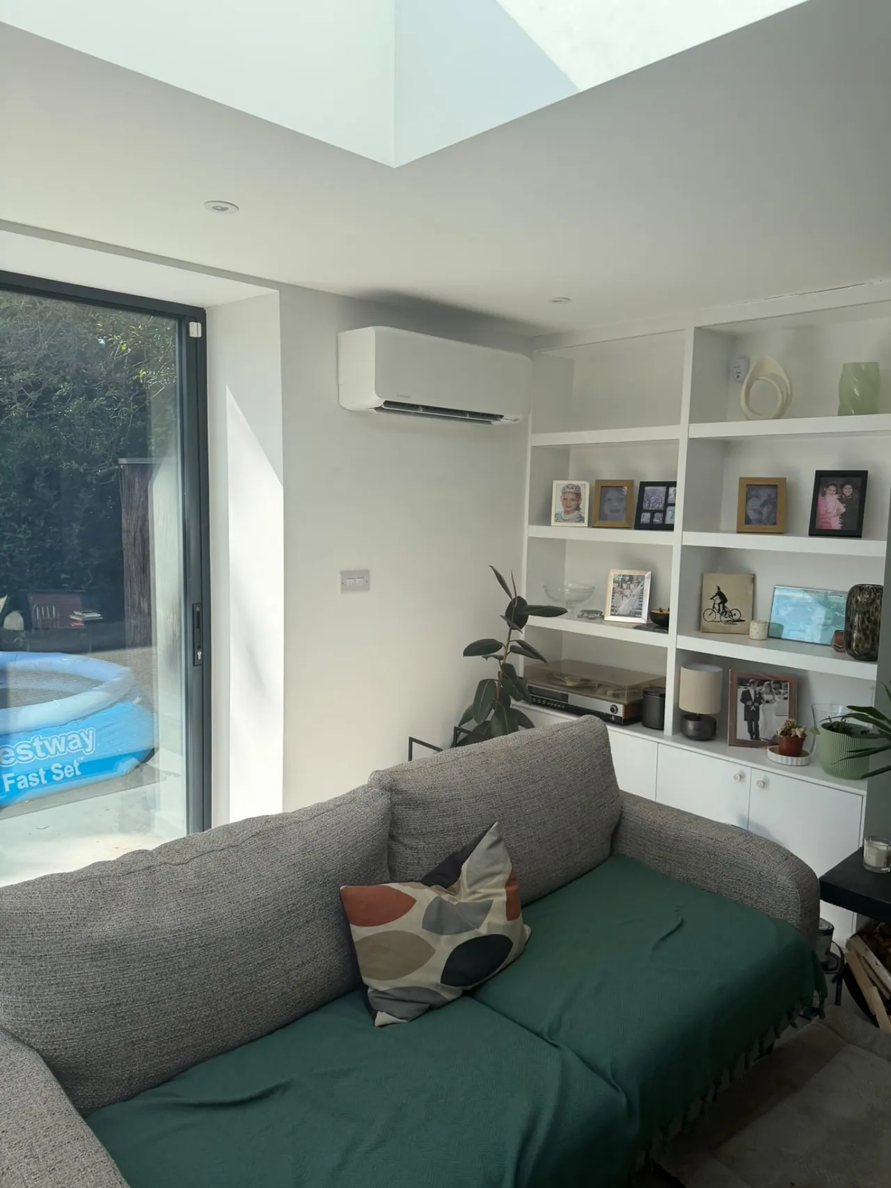 Wall-mounted air conditioning unit installed in a bright living room with patio doors