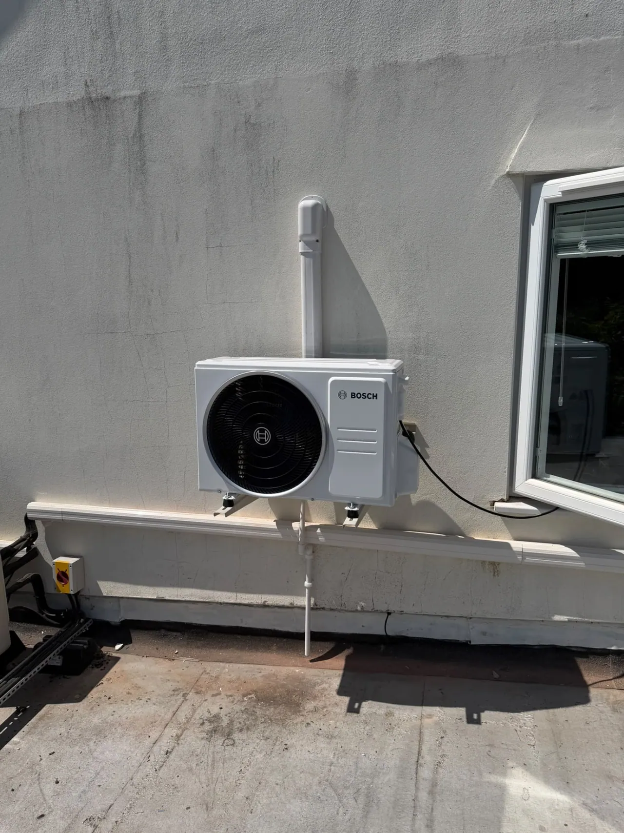 Bosch air conditioning outdoor condenser installed on a rendered wall