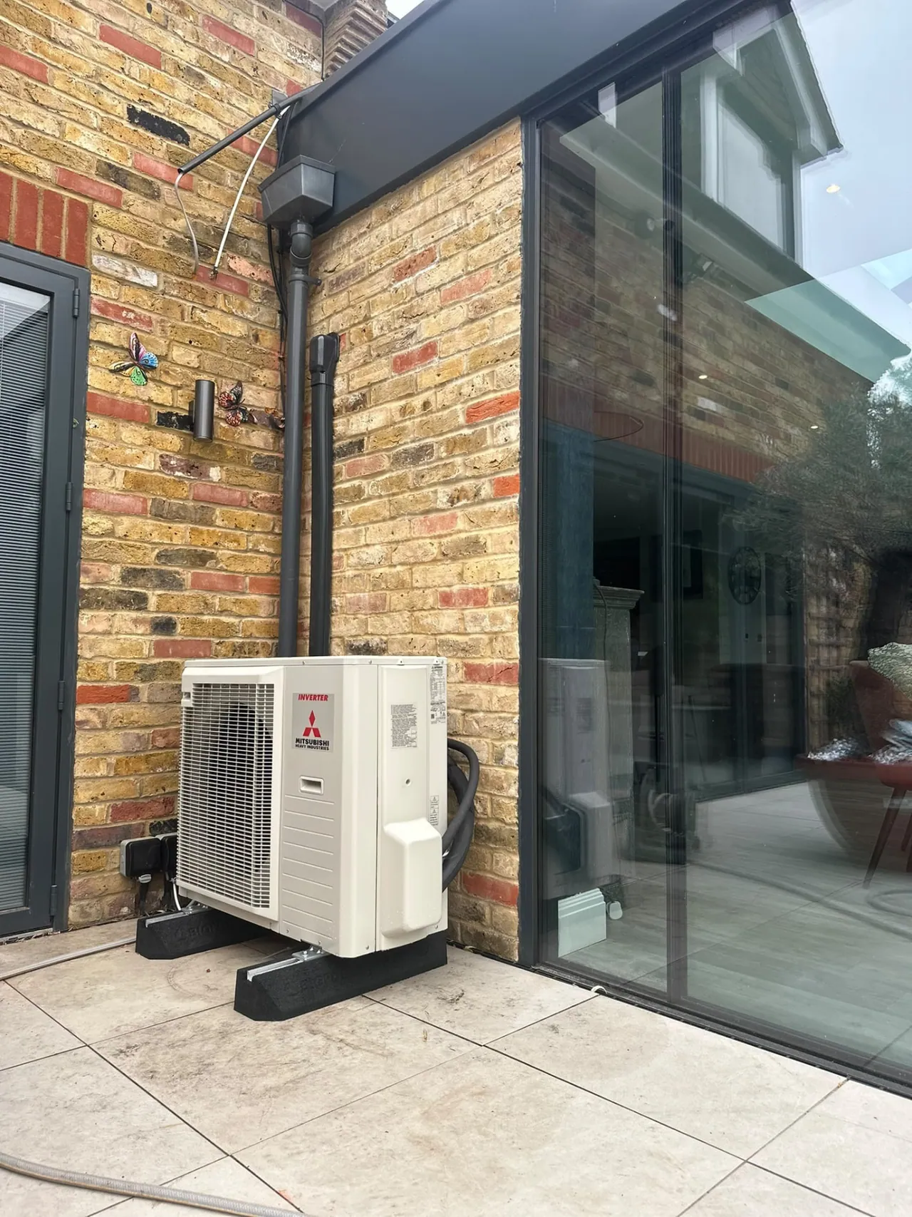 Mitsubishi air conditioning outdoor condenser installed beside a glazed rear extension