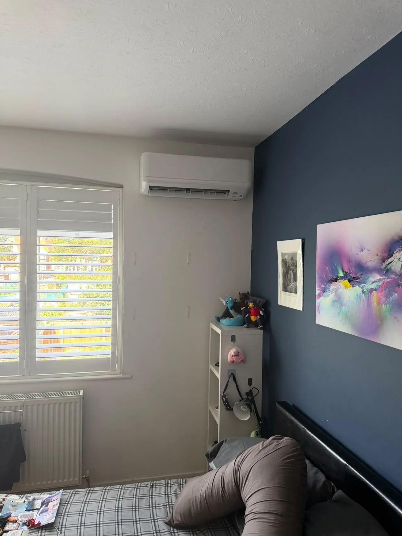 Wall-mounted air conditioning unit installed on a navy bedroom feature wall
