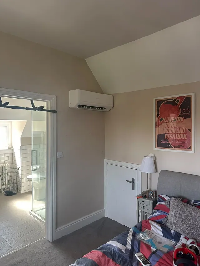 Wall-mounted air conditioning unit installed in a loft bedroom with sloped ceiling