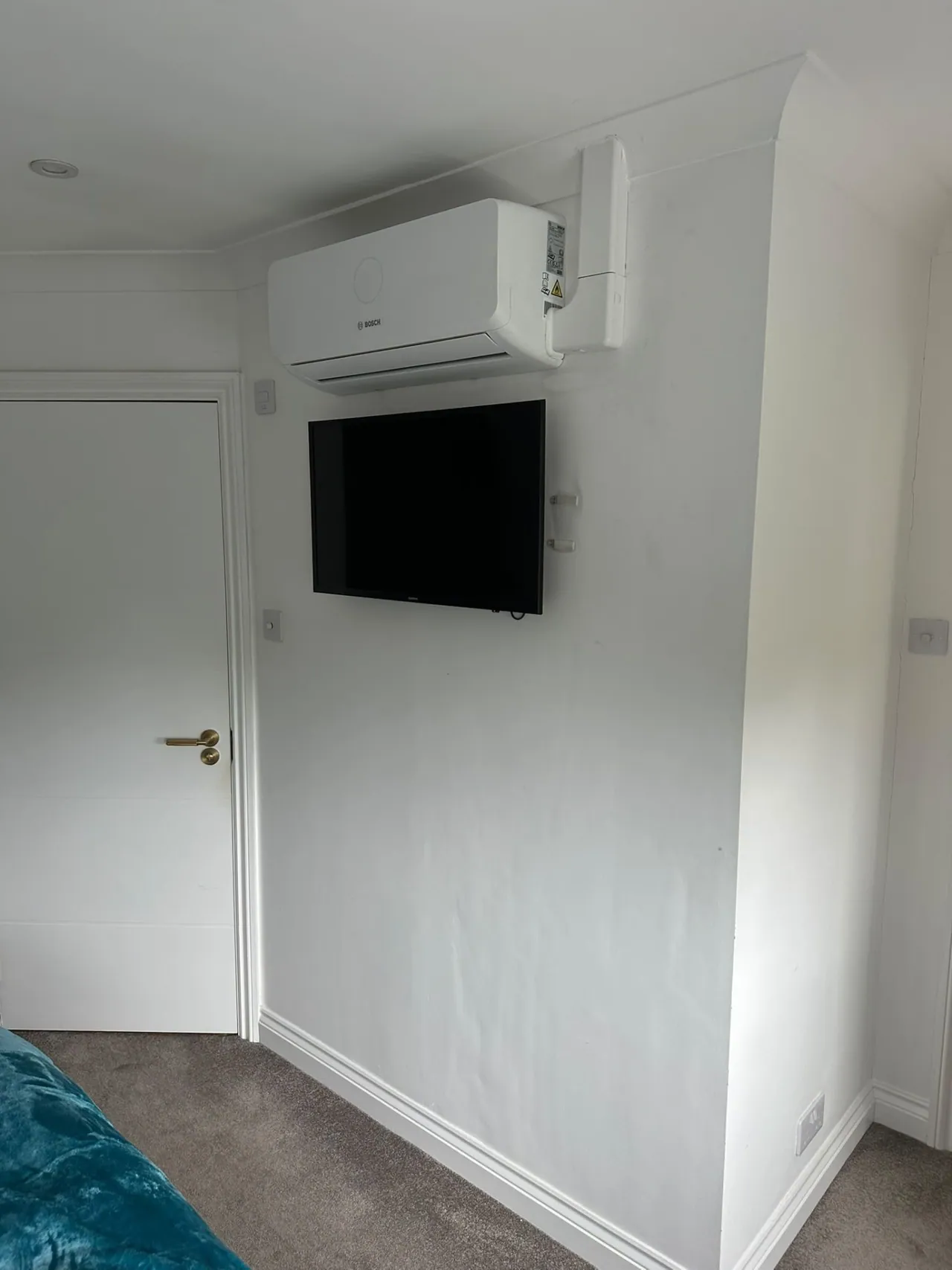 Bosch wall-mounted air conditioning above a television in a bedroom